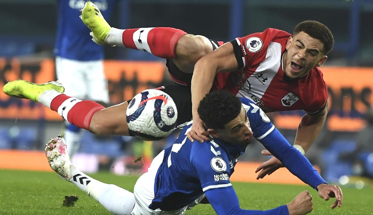 Gelandang Southampton, Che Adams (atas) dan gelandang Everton, Ben Godfrey terjatuh usai perebutan bola dalam laga lanjutan Liga Inggris 2020/21 pekan ke-26 di Goodison Park, Liverpool, Senin (1/3/2021). Southampton kalah 0-1 dari Everton. (AP/Gareth Copley/Pool)
