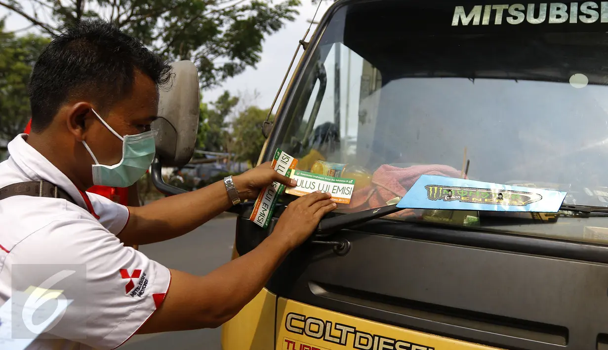 Petugas menempelkan stiker tanda lulus uji emisi di kendaraan usai melakukan pengujian kendaraan, Depok, Rabu (4/11/2015).Kemeterian Lingkungan Hidup dan Kehutanan RI gelar uji emisi kendaraan roda empat secara gratis di Depok. (Liputan6.com/Yoppy Renato)
