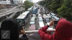 Warga mengabadikan kemacetan yang terjadi di Jalan Salemba Raya, Jakarta, Jumat (2/12). Tingginya mobilisasi massa yang akan mengikuti Aksi 2 Desember mengakibatkan sejumlah ruas jalan menuju Monas macet total. (Liputan6.com/Immanuel Antonius)