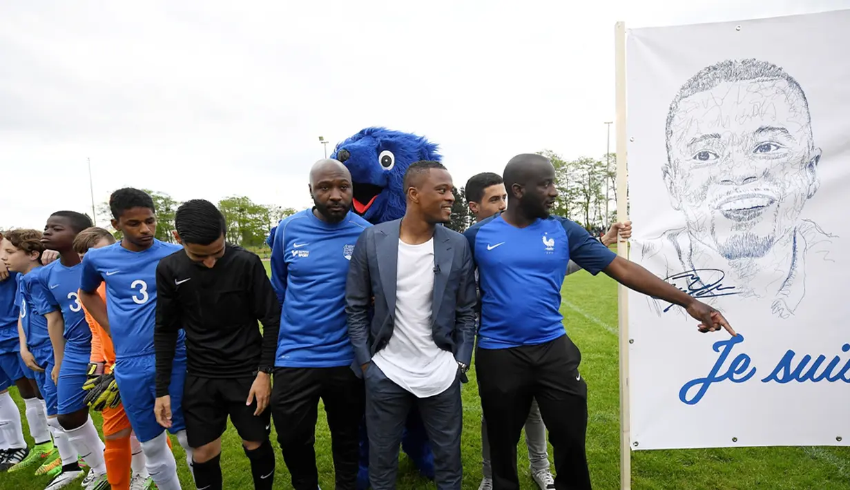 Pemain Timnas Prancis, Patrice Evra, berpose dengan para pemain muda Les Ulis di lapangan latihan Les Ulis di samping poster bergambar dirinya, (23/5/2016). (AFP/Franck Fife)