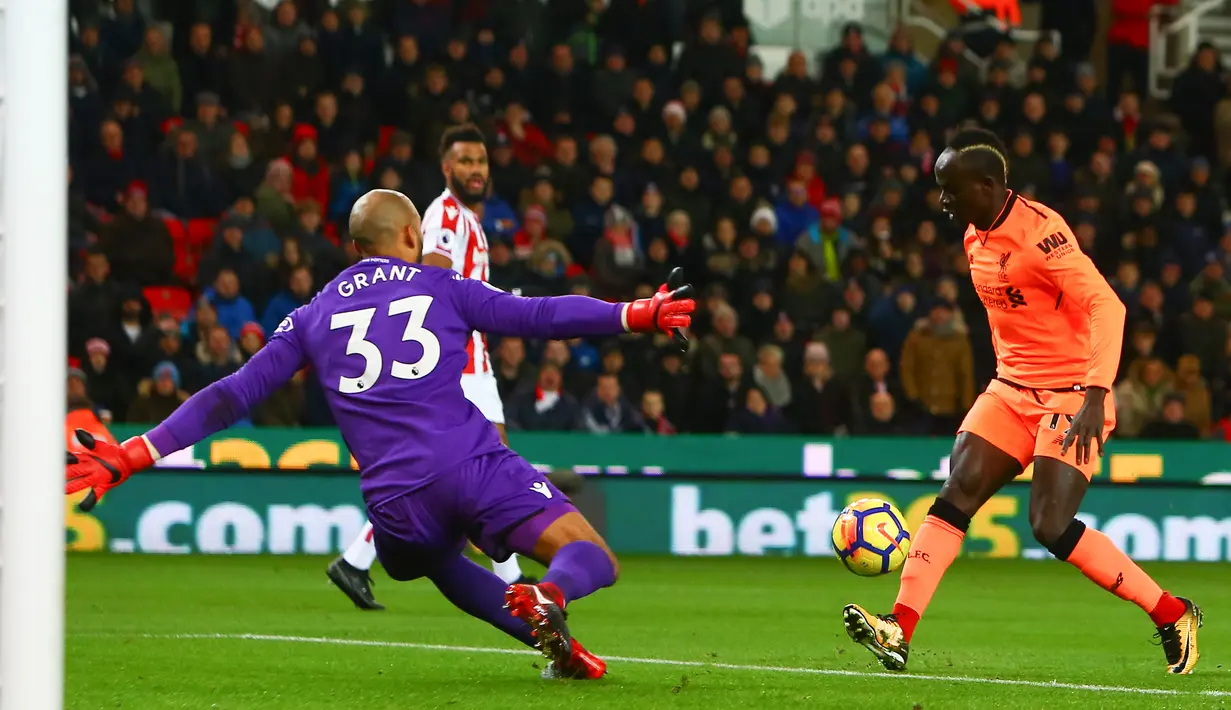 Gelandang Liverpool, Sadio Mane berlari melewati kiper Stoke City, Lee Grant untuk mencetak gol pada pekan ke-14 Premier League di Bet365 Stadium, Kamis (30/11). Liverpool berhasil membantai Stoke City dengan skor 3-0. (Geoff CADDICK/AFP)