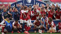 Striker Arsenal, Pierre-Emerick Aubameyang (tengah) menjatuhkan trofi saat merayakan gelar juara Piala FA usai mengalahkan Chelsea pada pertandingan final Piala FA di stadion Wembley, Minggu (2/8/2020).  Aubameyang terlihat kaget sambil memegang kepalanya saat trofi terjatuh. (Adam Davy/Pool via AP)