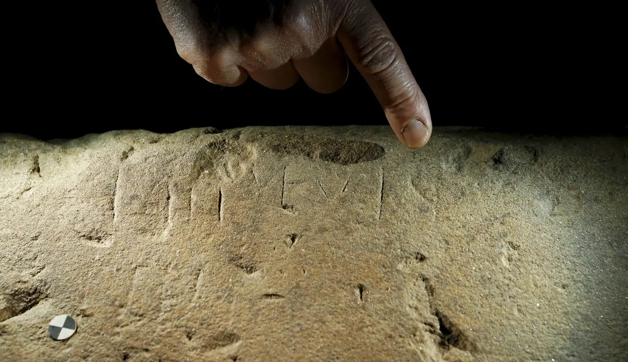 Seorang pakar sejarah menunjuk salah satu teks atau prasasti  di Florence , Italia , 20 April 2016. Teks prasasti-nya sendiri tertulis dengan bahasa yang sudah lama hilang dan ilmuwan kini sedang mendalami teks - teks tersebut. (REUTERS / Remo Casilli)