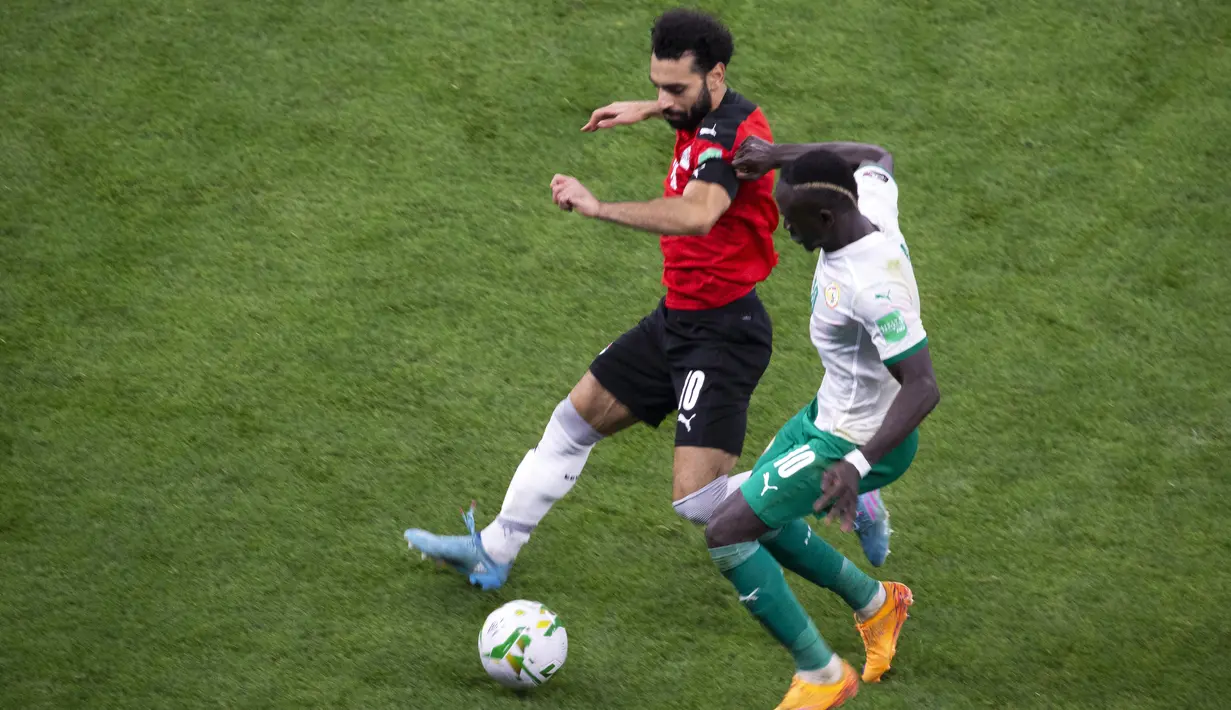 Penyerang Mesir Mohamed Salah berebut bola dengan penyerang Senegal Sadio Mané pada Kualifikasi Piala Dunia 2022 zona Afrika di Stade Me Abdoulaye Wade, Rabu (30/3/2022) dini hari WIB. Senegal dipastikan lolos ke Piala Dunia 2022 setelah menang adu penalti atas Mesir 3-1 (AP Photo/Stefan Kleinowitz)