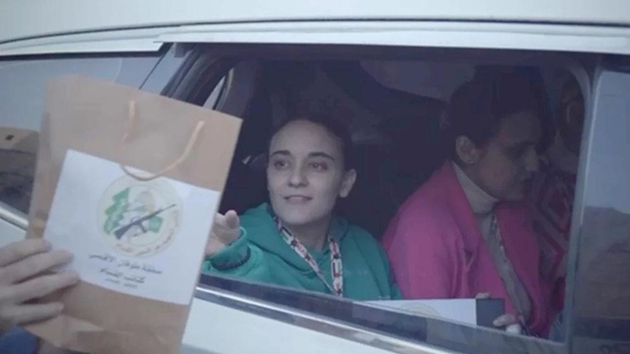 Seorang militan Hamas menyerahkan kantong kerta kepada Emily Damari saat dia diserahkan kepada Palang Merah di Gaza pada Minggu (19/1/2025).