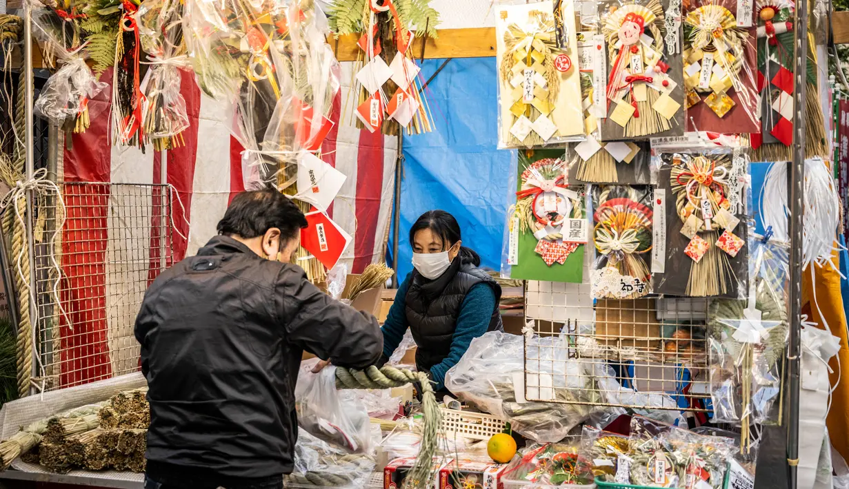 Seorang pria membeli dekorasi tahun baru di pekan raya akhir tahun di Distrik Nihonbashi, Tokyo, Jepang, 26 Desember 2022. Tak hanya menyuguhkan pemandangan indah dan makanan yang lezat, Jepang juga menjadi negara yang tepat untuk merayakan tahun baru. (Yuichi YAMAZAKI/AFP)