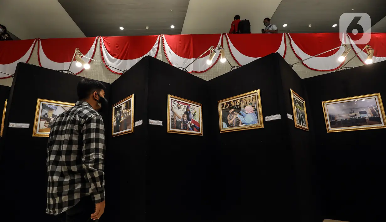 Pengunjung melihat karya foto dalam Pameran Foto Jurnalistik Warna-Warni Parlemen dengan tema Bangkit Lebih Cepat di loby Nusantara II DPR, Senayan, Jakarta, Senin (29/8/2022). Pada pameran Warna-warni Parlemen tahun ini terkumpul 1.200 karya foto, 101 di antaranya turut dipamerkan. (Liputan6.com/Johan Tallo)