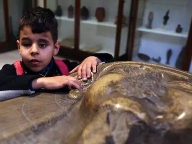 Seorang anak penyandang tunanetra menyentuh sebuah artefak di Museum Mesir di Kairo, Mesir (13/1/2020). Museum ini adalah rumah bagi koleksi antik bangsa Mesir kuno dan memiliki 120.000 koleksi. (Xinhua/Ahmed Gomaa)