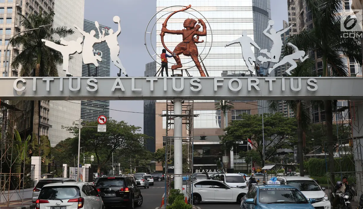 Pekerja membersihkan ornamen orang memanah di gerbang masuk jalan Pintu Satu Senayan, Jakarta, Jumat (20/7). Jelang perhelatan Asian Games 2018, sejumlah fasilitas penunjang di kawasan Gelora Bung Karno terus dipercantik. (Liputan6.com/Helmi Fithriansyah)