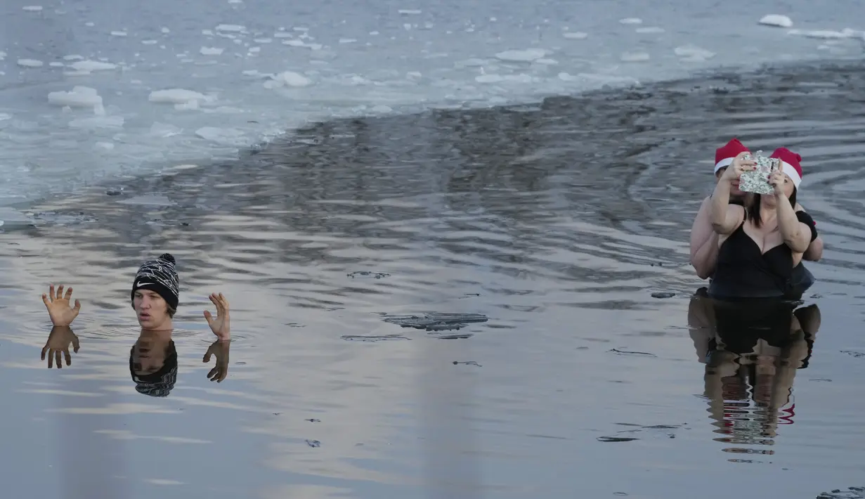 Orang-orang berenang di danau dengan suhu di bawah titik beku di Warsawa, Polandia (26/12/2021). Iklim di Polandia pada musim dingin yang sangat dingin, seringkali di bawah titik beku (0 °C atau 32 °F), dan musim panas yang hangat.  (AP Photo/Czarek Sokolowski)