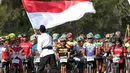 Para pebalap menyanyikan lagu Indonesia Raya sebelum melakukan start Mountain Bike Cross Country Marathon pada Festival Pesona Tanjung Lesung 2017 di Tanjung Lesung, Banten (23/9/2017). MTB XCM tersebut menempuh jarak 48 km. (Bola.com/Nicklas Hanoatubun)