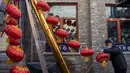 Seorang pekerja memasang lentera tradisional Tiongkok di sepanjang gang menjelang Tahun Baru Imlek di Beijing, China, 2 Februari 2021. Imlek tahun ini jatuh pada tanggal 12 Februari 2021. (NOEL CELIS/AFP)