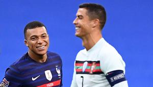 Striker Prancis, Kylian Mbappe, tersenyum kepada striker Portugal, Cristiano Ronaldo, pada laga UEFA Nations League di Stadion Stade de France, Senin (12/10/2020). Kedua tim bermain imbang 0-0. (AFP/Franck Fife)