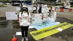 Aksi berupa patung es dalam pengantaran 1000 kartu pos oleh aktivis Greenpeace kepada Presiden Joko Widodo di kawasan Monumen Patung Kuda, Jakarta, Rabu (10/11/2021). Kartu pos itu berisikan agar pemerintah melihat dampak perubahan iklim terhadap ekosistem di sekitar. (Liputan6.com/Faizal Fanani)