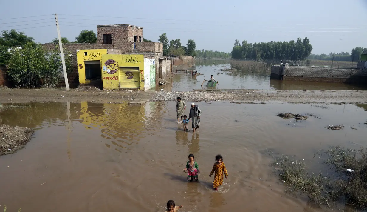 Orang-orang mengarungi banjir di Charsadda, Pakistan, Rabu (31/8/2022). Para pejabat di Pakistan menyampaikan kekhawatiran Rabu atas penyebaran penyakit yang ditularkan melalui air di antara ribuan korban banjir saat air banjir dari hujan monsun yang kuat mulai surut di banyak bagian negara. (AP Photo/Mohammad Sajjad)
