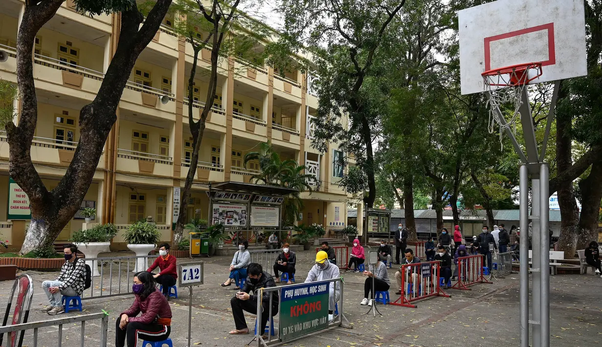 Penduduk memakai masker mengantre dengan tertib saat akan mengikuti pengujian Covid-19 di pusat pengujian dekat rumah sakit Bach Ma, Hanoi, Vietnam (31/3/2020). Warga Vietnam antusias mengikuti tes Covid-19 dengan tertib di tengah masifnya penyebaran Covid-19 di dunia. (AFP/Manan Vatsyayana)