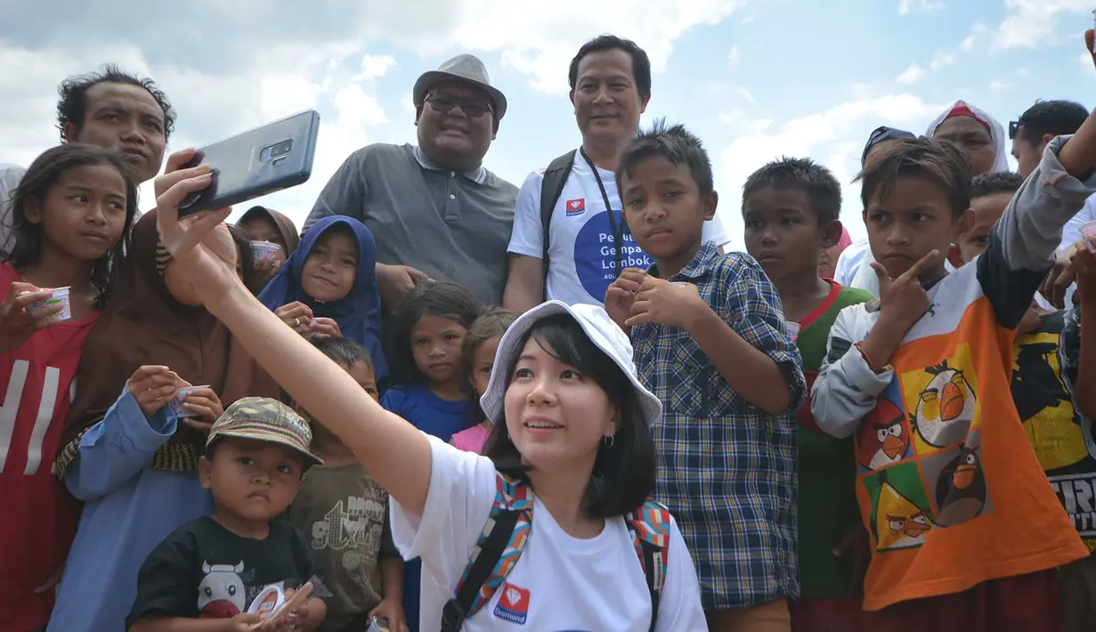 Jajaran direksi Diamond Group serta karyawan berswafoto bersama para pengungsi gempa Lombok saat kegiatan CSR Diamond Group Peduli  di Dusun Trengan Timur, Kecamatan Pamenang Kabupaten Lombok Utara, Nusa Tenggara Barat, Sabtu (8/9). (Liputan6.com/HO/Eko)