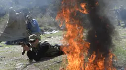 Api berkobar saat pasukan ikut serta dalam latihan gabungan Kyrgyzstan dan India di Ngarai Tatyr, selatan Bishkek, dekat Desa Arashan, Kyrgyzstan, Senin (26/4/2021). Pasukan tersebut berlatih untuk mengoordinasikan aksi mereka melawan militan. (AP Photo/Vladimir Voronin)