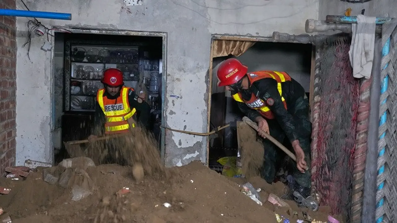 Petugas penyelamat mencari korban di antara reruntuhan bangunan yang ambruk di Lahore, Pakistan.