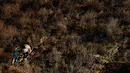 Seorang wanita dan anak migran memanjat bukit di San Ysidro, California, setelah memanjat pagar perbatasan AS (3/12). (AP Photo/Rebecca Blackwell)