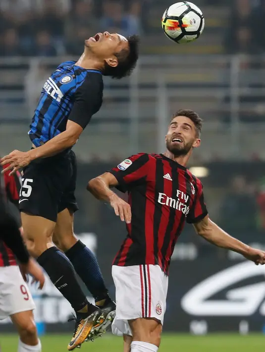 Pemain Inter Milan, Yuto Nagatomo menyundul bola di depan pemain AC Milan, Fabio Borini pada pekan kedelapan Liga Italia di Stadion Giuseppe Meazza, Minggu (15/10). Gol Inter Milan diborong oleh Mauro Icardi, 3-2. (AP/Antonio Calanni)
