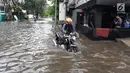 Pengendara mendorong motor yang mogok melintasi banjir di kawasan Green Garden, Jakarta Barat, Selasa (5/3). Banjir di kawasan tersebut disebabkan curah hujan tinggi, luapan air karena rob, dan air kiriman dari Bogor. (merdeka.com/Arie Basuki)