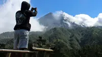 Seorang pria mengambil gambar Gunung Merapi di Cangkringan, Indonesia, Selasa, (22/5). Pihak berwenang meningkatkan kewaspadaan terhadap Gunung Merapi yang bergejolak di pulau Jawa. (AP Photo/A.K. Hendratmo)