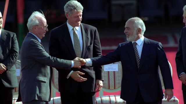 PM Israel Yitzhak Rabin (kiri) bersalaman dengan Raja Hussein dari Yordania (kanan) usai menyepakati perdamaian kedua negara, dimediasi oleh Presiden AS Bill Clinton (tengah) pada 26 Oktober 2020 (Government Press Office Israel)