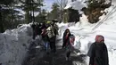 Wisatwan berjalan di sepanjang jalan Bukit Murree yang tertutup salju, Pakistan, 9 Januari 2022. Sebanyak 22 wisatawan tewas saat sekitar 1.000 kendaraan terjebak salju tebal di Bukit Murree. (Aamir QURESHI/AFP)