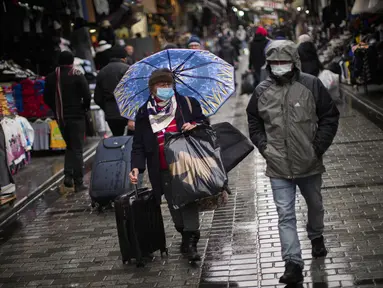 Warga yang mengenakan masker berjalan di Istanbul, Turki, Rabu (12/1/2022). Meskipun COVID-19 melonjak, negara itu sejauh ini tidak mempertimbangkan untuk memberlakukan pembatasan baru tetapi mendesak orang tetap menggunakan masker dan melakukan social distancing. (AP Photo/Francisco Seco)
