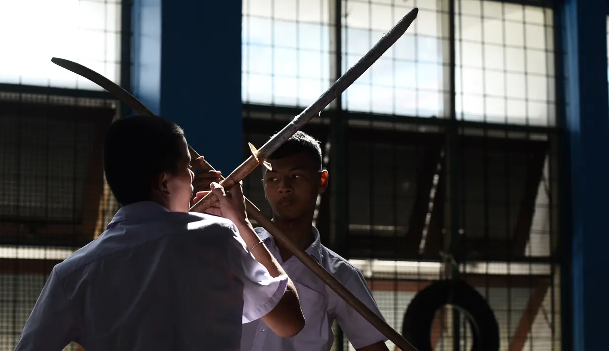 Dua siswa menggunakan pedang berlatih Krabi Krabong di sekolah Thonburee Woratapeepalarak, Thonburi, Bangkok (8/7/2019). Krabi Krabong merupakan seni bela diri Thailand yang dipersenjatai pisau dan perisai kayu yang terabaikan. (AFP Photo/Lillian Suwanrumpha)