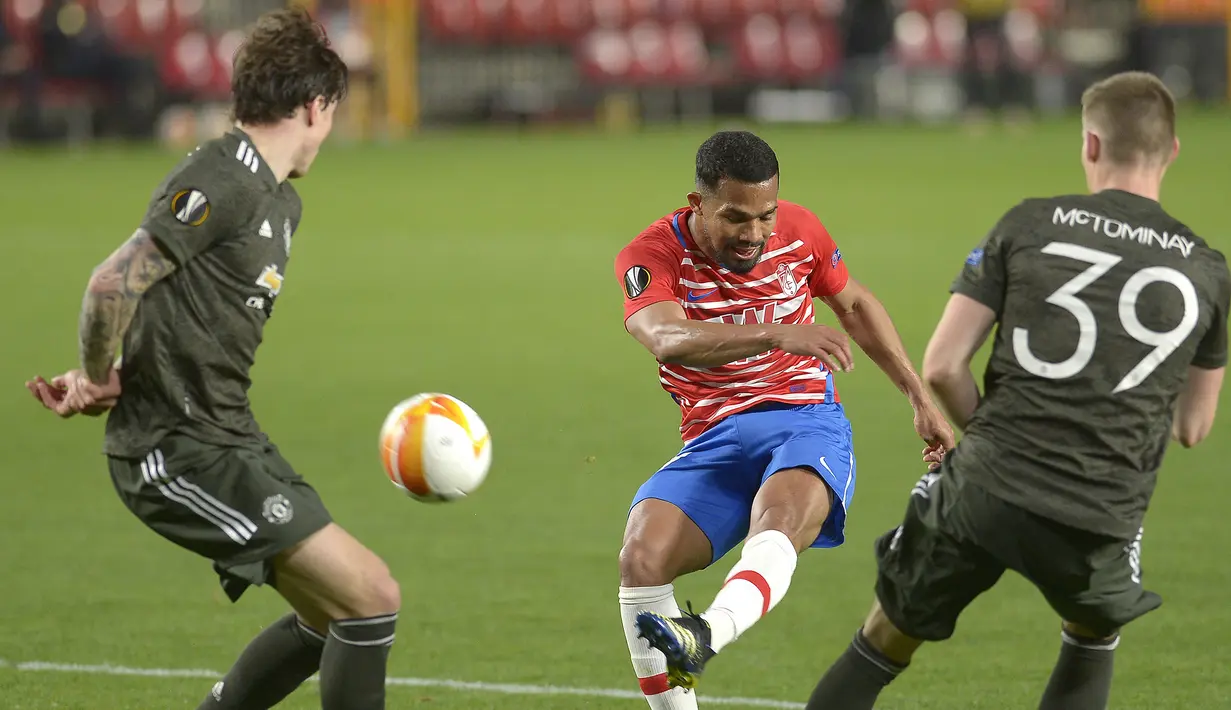 Gelandang Granada, Yangel Herrera (tengah) melepaskan tendangan ke gawang Manchester United dalam laga leg pertama perempatfinal Liga Europa 2020/2021 di Nuevo Los Carmenes Stadium, Granada, Kamis (8/4/2021). Granada kalah 0-2 dari Manchester United. (AFP/Cristina Quicler)