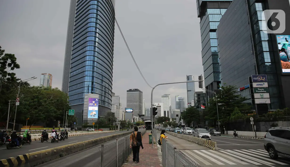 Sejumlah pekerja berjalan di kawasan Jalan Sudirman, Jakarta, Selasa (2/11/2021). Sektor non-esensial kini boleh mempekerjakan hingga 75 persen karyawannya dari kantor. Sebelumnya, angka ini dibatasi hingga 50 persen. (Liputan6.com/Faizal Fanani)