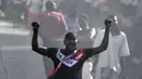 Seorang pria memprotes meningkatnya kekerasan di tengah asap dari ban yang dibakar oleh demonstran di lingkungan Lalue, Port-au-Prince, Haiti, Rabu (14/7/2021). Presiden Haiti Jovenel Moise dibunuh pada 7 Juli. (AP Photo/Matias Delacroix)