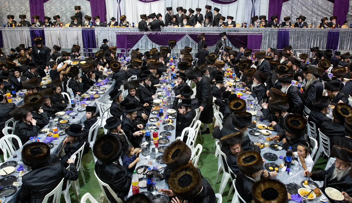 Orang-orang Yahudi ultra-ortodoks mendapat jamuan makanan saat menghadiri upacara pernikahan Hannah Halbershtam dan Menahem Nachum putra Rabi dari Dinasti Hasvor Nadvorna di kota ultra-ortodoks Bnei Brak, Israel, Selasa (20/8/2019. (AP Photo/Oded Balilty)