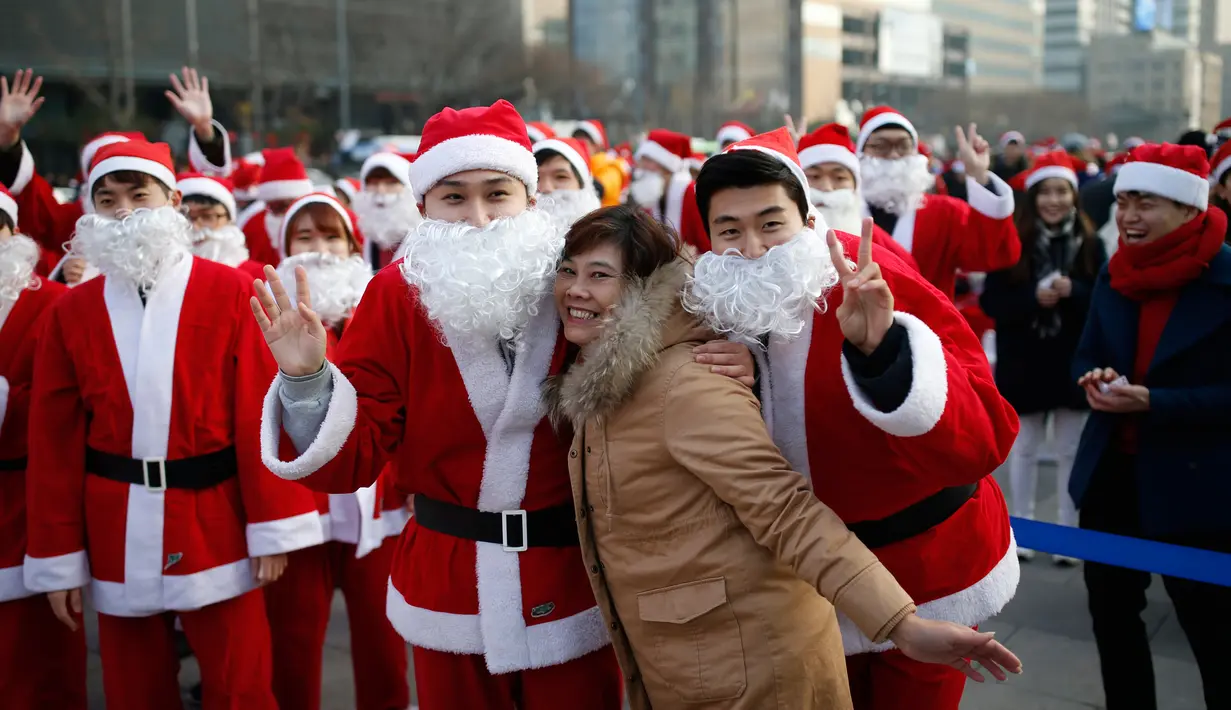 Seorang turis berfoto bersama dengan orang berpakaian seperti Santa Claus saat acara amal Natal di pusat kota Seoul, Korea Selatan, (24/12/2015). (REUTERS/Kim Hong-Ji)