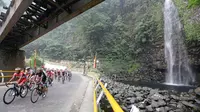 Para pebalap sedang melewati air terjun Lembah Anai, Kabupaten Tanah Datar dalam Etape 6 Tour de Singkarak 2015, Kamis (8/10/2015). (Bola.com/Arief Bagus)