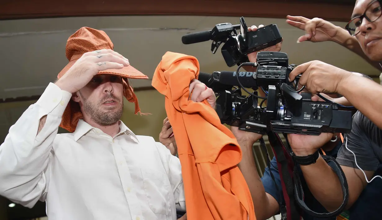 Joshua James Baker menutupi wajahnya usai menjalani sidang di pengadilan Denpasar, Bali (23/1). Polisi menangkap Baker di Bandara Ngurah Rai dari Bangkok 8 Oktober 2017 setelah membawa obat-obatan terlarang. (AFP Photo/Sonny Tumbelaka)
