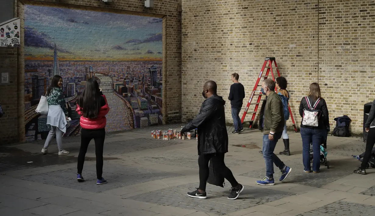 Seniman jalanan Australia James Cochran, juga dikenal sebagai Jimmy C, (kiri keempat) melihat karyanya saat dia memberikan sentuhan akhir pada mural lanskap kota London-nya di dinding Network Rail oleh Blackfriars Station, di London (5/10/2020). (AP Photo/Matt Dunham)