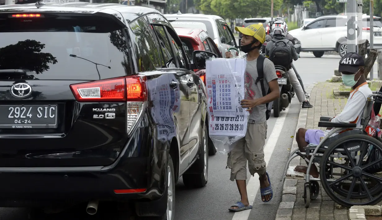 Pedagang menawarkan kalender tahun 2021 kepada pengguna jalan di perempatan Pondok Pinang, Kebayoran, Jakarta Selatan, Senin (7/12/2020). Jelang pergantian tahun, sejumlah pedangang mulai menjajakan kalender tahun 2021 dengan harga Rp 20 ribu-Rp 40 ribu tergantung ukuran. (merdeka.com/Dwi Narwoko)