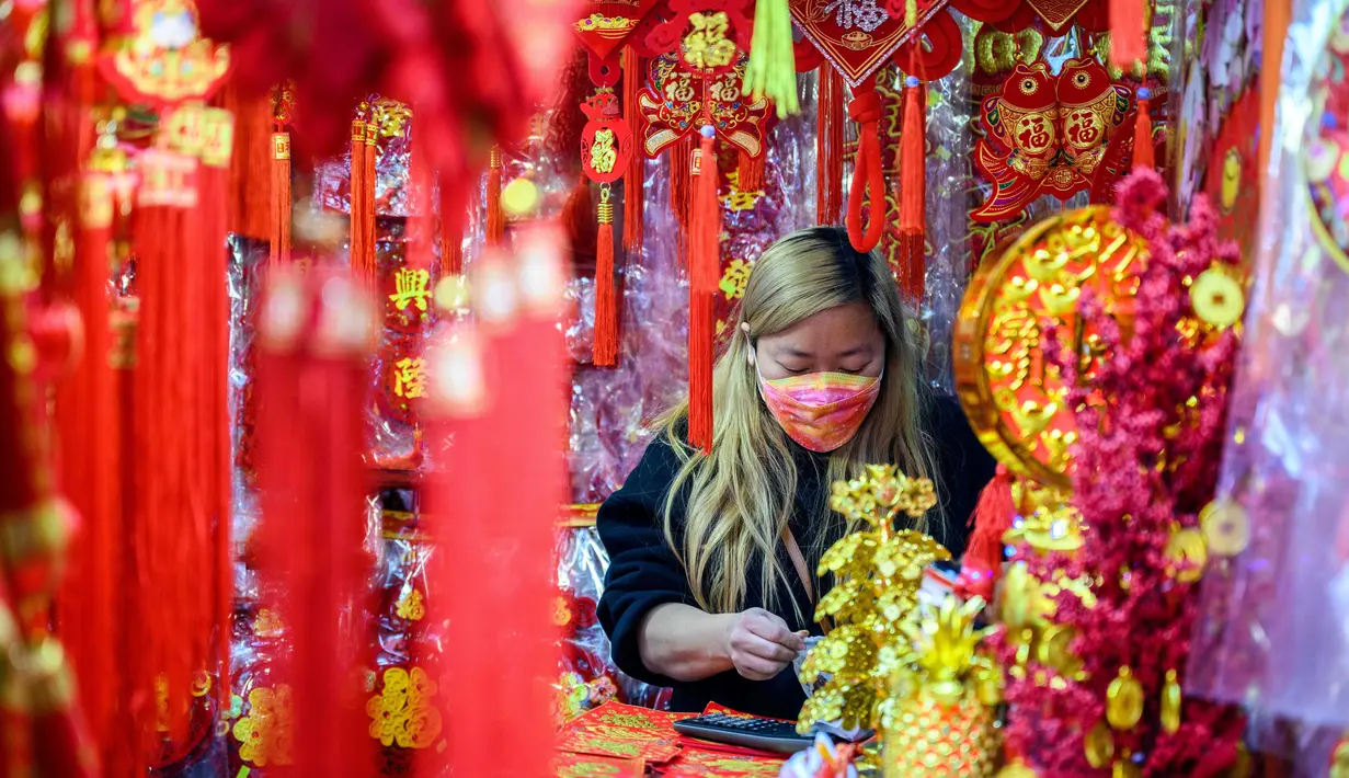 Seorang vendor menunggu pelanggan di kiosnya yang menjual dekorasi di Hong Kong (15/1/2021). Warga Hong Kong mulai berburu pernak-pernik Tahun Baru Imlek seperti lampion, kartu Imlek, baju, dan hiasan rumah. (AFP/Anthony Wallace)