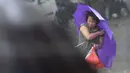 Seorang wanita memegang payung saat berjalan di tengah hembusan Topan Kalmaegi yang menerjang wilayah Qionghai di provinsi Hainan, Tiongkok, (16/9/2014). (REUTERS/Stringer)