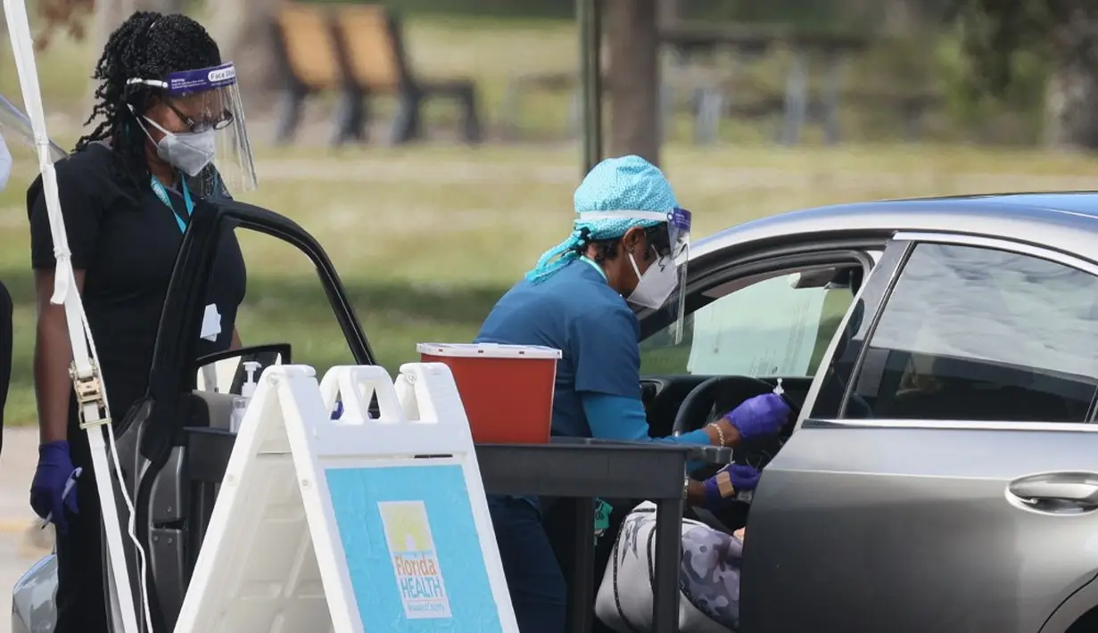 Petugas kesehatan bersiap untuk memberikan vaksin virus corona COVID-19 secara drive-thru di Vista View Park, Davie, Florida, Amerika Serikat, 4 Januari 2021. Lokasi vaksinasi COVID-19 drive-thru tersebut disiapkan untuk penduduk Broward yang berusia 65 tahun ke atas. (Joe Raedle/Getty Images/AFP)
