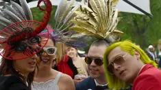 Para Racegoers berpose menggunakan hiasan kepala dan menggunakan gaun mewah yang saat menghadiri balap kuda Melbourne di arena pacuan kuda Flemington Racecourse di Melbourne, Australia (1/11). (AFP/Paul Crock)