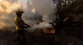 Petugas pemadam berupaya memadamkan api di lokasi jembatan yang terbakar di perbukitan Big Pines dekat Wrightwood, California. pada tanggal 12 September 2024. (ETIENNE LAURENT/AFP)