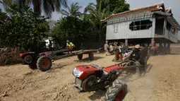 Warga menggunakan traktor untuk memindahkan rumah di Desa Serey Andet di provinsi Kampong Speu, Kamboja (27/3). Mereka memindahkan rumah dengan cara tersebut dengan tujuan agar rumah tetap utuh. (AP Photo/Heng Sinith)
