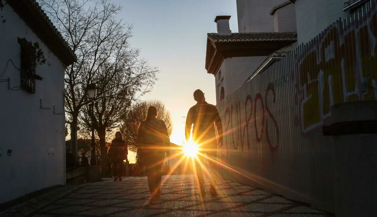 Pasangan berjalan melalui distrik bersejarah Albaicin saat matahari terbenam di Granada, Spanyol, (12/3). Distrik ini dinyatakan sebagai Situs Warisan Dunia UNESCO pada tahun 1984. (AP Photo/Mosa'ab Elshamy)
