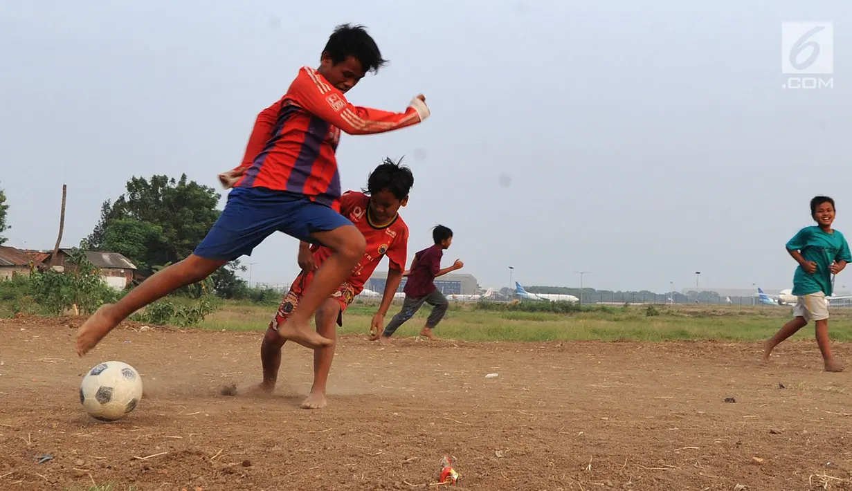 Anak-anak bermain bola di kawasan proyek perluasan landasan pacu atau Runway 3A Bandara Soekarno-Hatta (Soetta), Rawa Bokor, Tangerang, Banten, Selasa (2/7/2019). Mereka memanfaatkan lahan kosong yang belum dikerjakan pihak kontraktor untuk bermain bola. (merdeka.com/Arie Basuki)