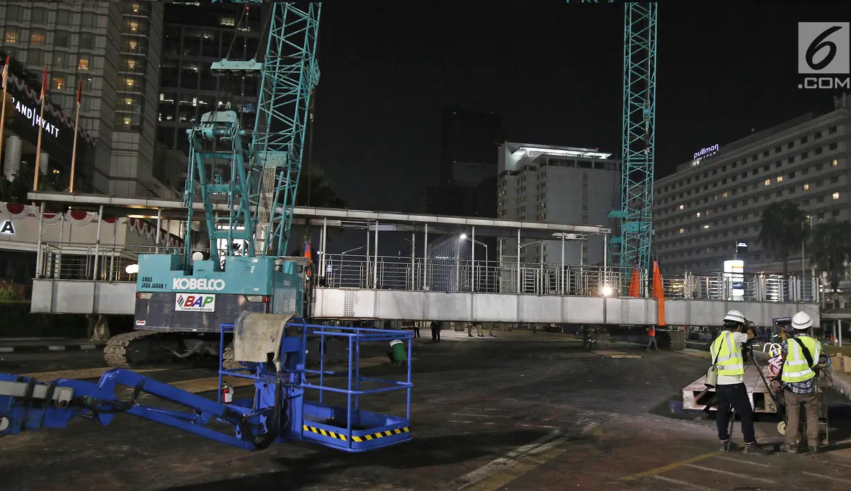 Petugas menggunakan alat berat merobohkan Jembatan Penyeberangan Orang (JPO) di Kawasan Bundaran HI, Jakarta, Senin (30/7/2018) malam. Pembongkaran JPO ini juga terkait upaya mempercantik ibu kota jelang Asian games 2018. (Liputan6.com/Herman Zakharia)