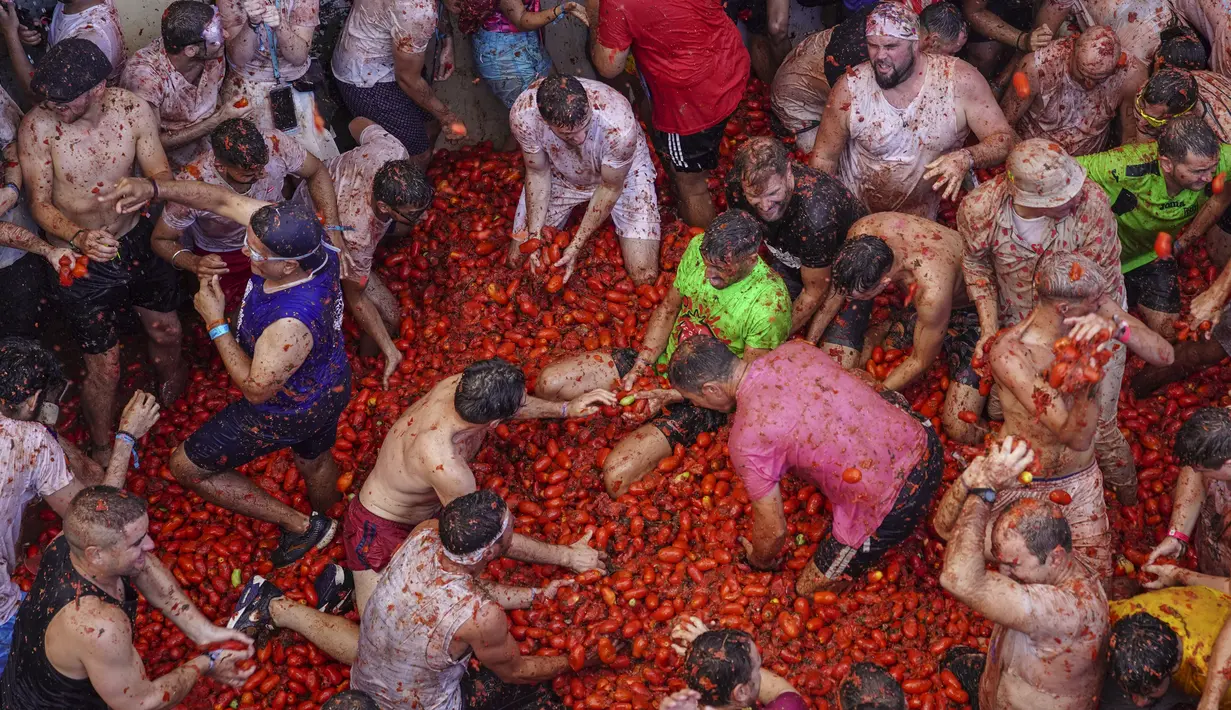 Orang-orang yang bersuka ria saling melempar tomat dalam acara tahunan "Tomatina", pesta pertarungan tomat di desa Bunol dekat Valencia, Spanyol, Rabu (31/8/2022). La Tomatina sering dianggap sebagai salah satu pertarungan makanan terbesar di dunia. (AP Photo/Alberto Saiz)